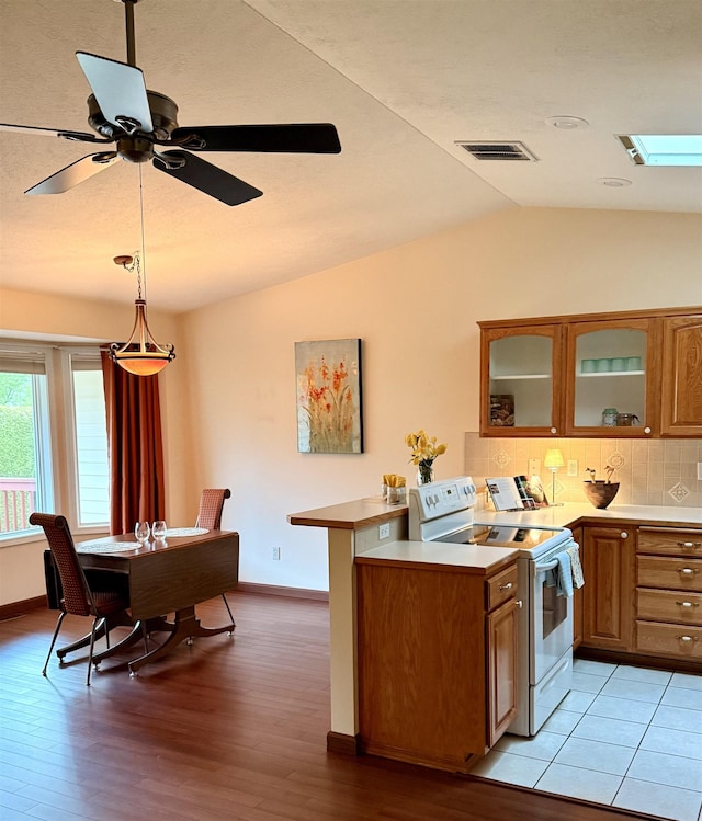 1610 S Newer Ln Unit 0, Spokane Valley, WA 99037 - kitchen featuring white electric range oven, brown cabinetry, vaulted ceiling, light countertops, and a peninsula
