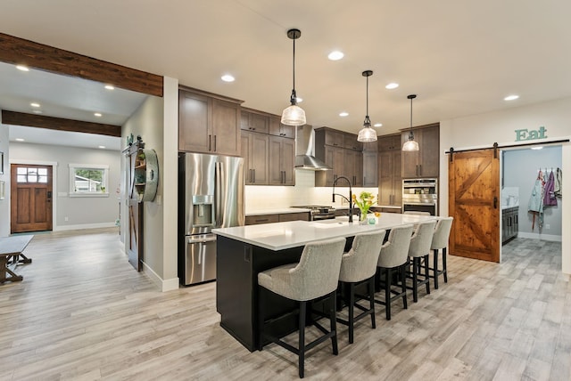 2007 E 33rd Ave, Spokane, WA 99203 - kitchen featuring appliances with stainless steel finishes, wall chimney range hood, a barn door, light countertops, and baseboards