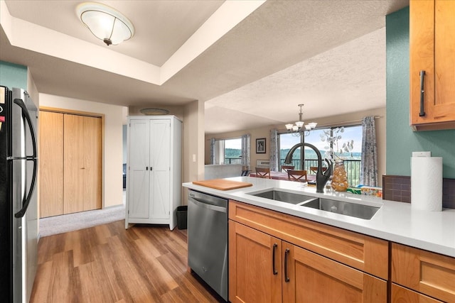 172 S Coeur Dalene St Unit G304, Spokane, WA 99204 - kitchen featuring stainless steel appliances, a sink, light countertops, light wood-style flooring, and a chandelier