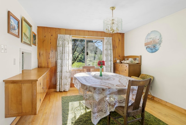 4345 Wilcox Rd, Northport, WA 99157 - dining area with a chandelier, light wood-style floors, wooden walls, and baseboards