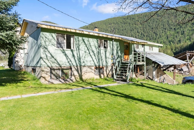 4345 Wilcox Rd, Northport, WA 99157 - rear view of property featuring a forest view, a lawn, stairway, and a chimney