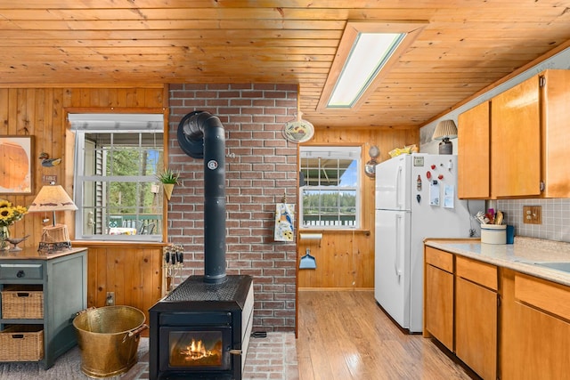231 Mountain View Dr, Newport, WA 99156 - kitchen with a wood stove, freestanding refrigerator, wood ceiling, wooden walls, and light wood-style flooring