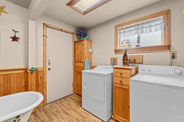 231 Mountain View Dr, Newport, WA 99156 - clothes washing area with washing machine and dryer, light wood-style floors, a wainscoted wall, wood walls, and a skylight