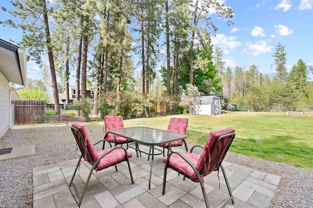 view of patio featuring outdoor dining space, a storage unit, and an outdoor structure