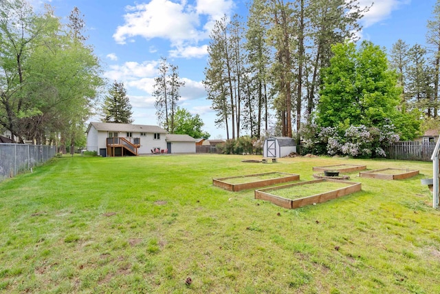 view of yard featuring a storage unit, a vegetable garden, an outdoor structure, and a wooden deck