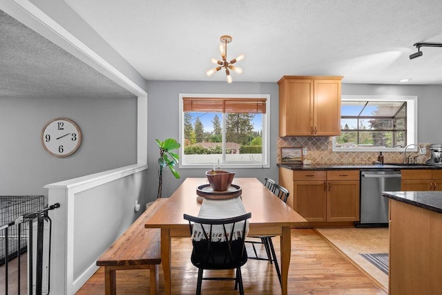 8214 N Jefferson Dr, Spokane, WA 99208 - kitchen with stainless steel dishwasher, a sink, dark countertops, backsplash, and light wood-style flooring