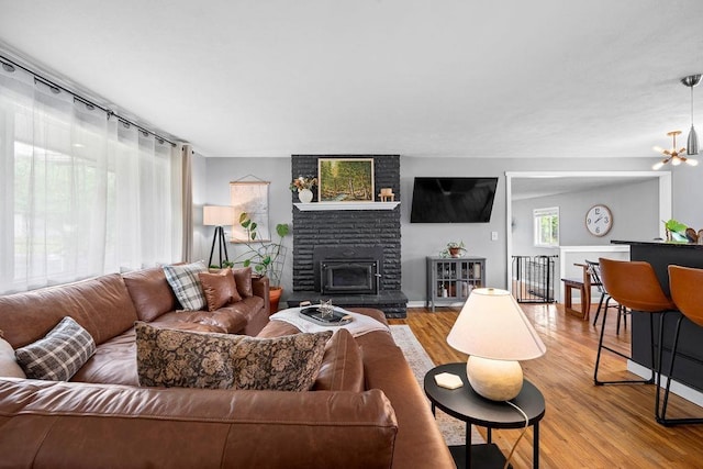 8214 N Jefferson Dr, Spokane, WA 99208 - living area with a brick fireplace, wood finished floors, a chandelier, and baseboards
