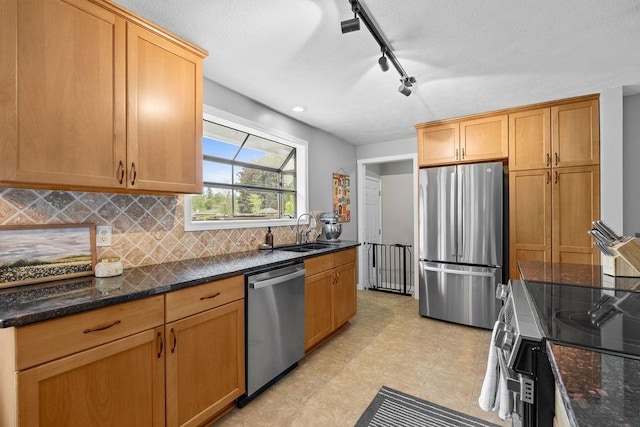 8214 N Jefferson Dr, Spokane, WA 99208 - kitchen featuring stainless steel appliances, track lighting, decorative backsplash, a sink, and dark stone counters