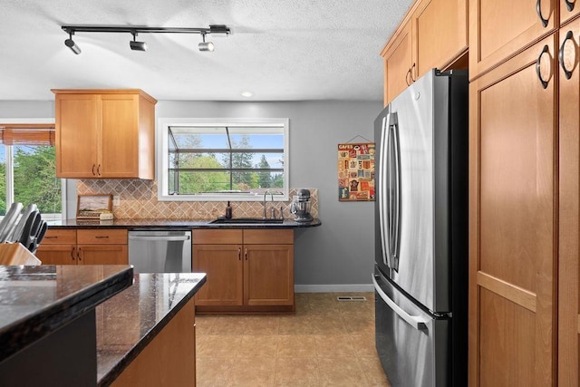 8214 N Jefferson Dr, Spokane, WA 99208 - kitchen featuring appliances with stainless steel finishes, a sink, decorative backsplash, dark stone countertops, and baseboards