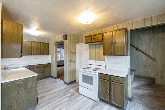 33 E Everett Ave, Spokane, WA 99207 - kitchen featuring white range with electric cooktop, tasteful backsplash, wood walls, light wood-style floors, and light countertops