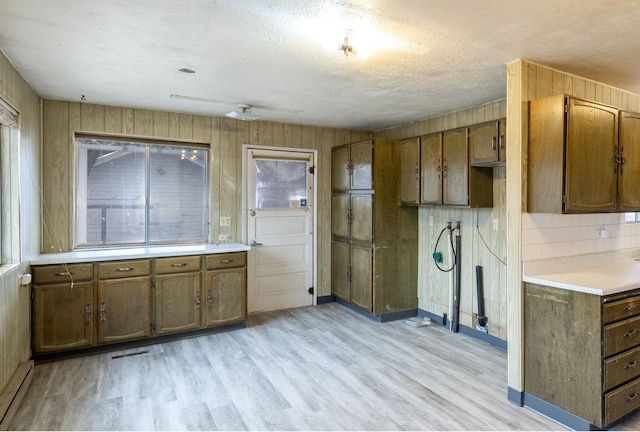 33 E Everett Ave, Spokane, WA 99207 - kitchen with a baseboard radiator, light wood-type flooring, brown cabinetry, wooden walls, and a textured ceiling