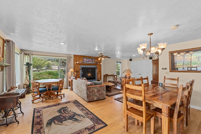 2443 Flowery Trail Rd, Usk, WA 99180 - dining space featuring a textured ceiling, light wood-style floors, a chandelier, a ceiling fan, and a tile fireplace