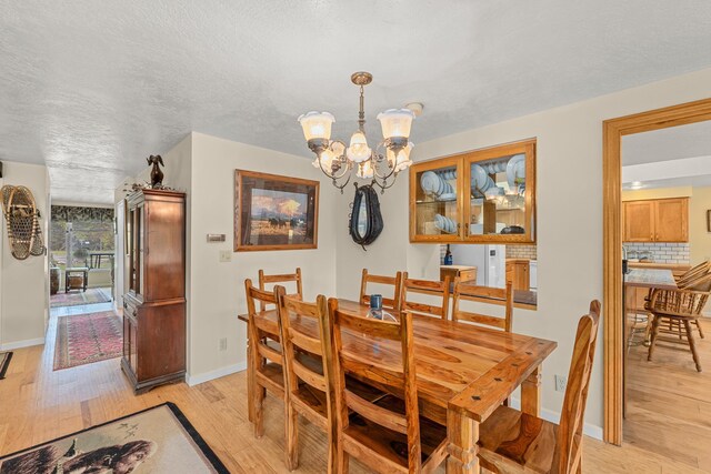 2443 Flowery Trail Rd, Usk, WA 99180 - dining space featuring light wood finished floors, a chandelier, baseboards, and a textured ceiling