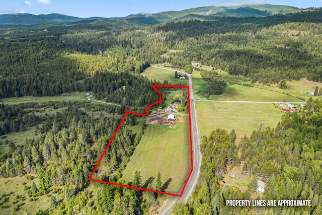 2443 Flowery Trail Rd, Usk, WA 99180 - aerial view of property and surrounding area with a heavily wooded area, property parcel outlined, and a mountainous background