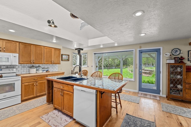 2443 Flowery Trail Rd, Usk, WA 99180 - kitchen featuring white appliances, a sink, a breakfast bar, brown cabinets, and a textured ceiling