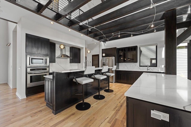 2503 S Thierman Ln, Spokane, WA 99223 - kitchen with stainless steel appliances, wall chimney range hood, a center island with sink, light countertops, and light wood-style flooring