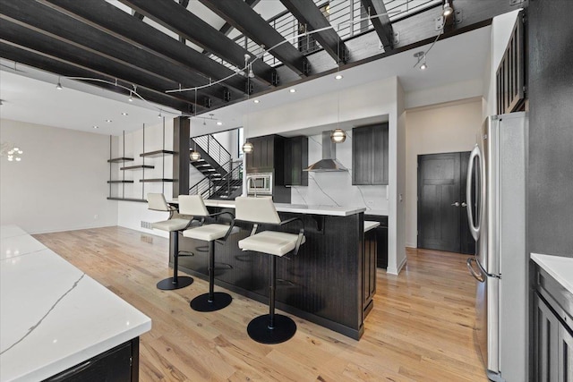 2503 S Thierman Ln, Spokane, WA 99223 - kitchen with appliances with stainless steel finishes, wall chimney exhaust hood, light wood-style flooring, light countertops, and dark cabinets