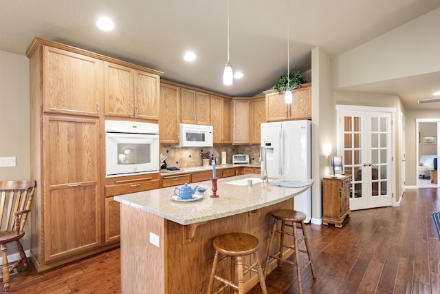 9016 N Sundance Dr, Spokane, WA 99208 - kitchen featuring white appliances, dark wood-style floors, light stone counters, a kitchen bar, and decorative backsplash