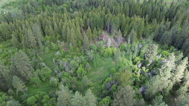 aerial view of property and surrounding area featuring a heavily wooded area