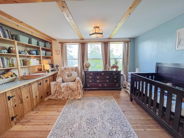 bedroom with beamed ceiling, light wood-style floors, and multiple windows
