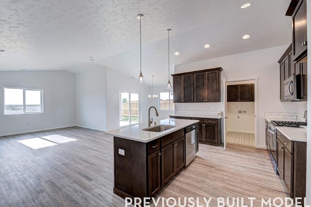 18806 E Riverside Ct, Spokane Valley, WA 99016 - kitchen with stainless steel appliances, a sink, lofted ceiling, light wood finished floors, and an island with sink