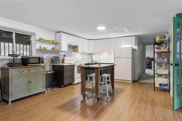11010 E 28th Ave, Spokane, WA 99206 - kitchen with white appliances, under cabinet range hood, open shelves, white cabinets, and light wood-style floors