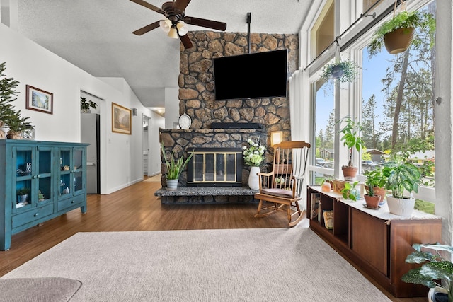 11010 E 28th Ave, Spokane, WA 99206 - living room featuring vaulted ceiling, ceiling fan, wood finished floors, a textured ceiling, and a stone fireplace