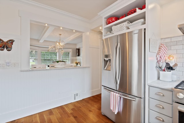 kitchen featuring appliances with stainless steel finishes, wood finished floors, a chandelier, beamed ceiling, and backsplash
