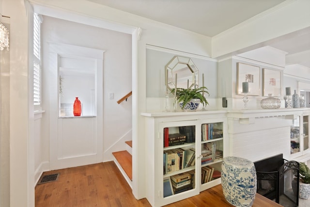 interior space featuring wood finished floors, crown molding, and stairs