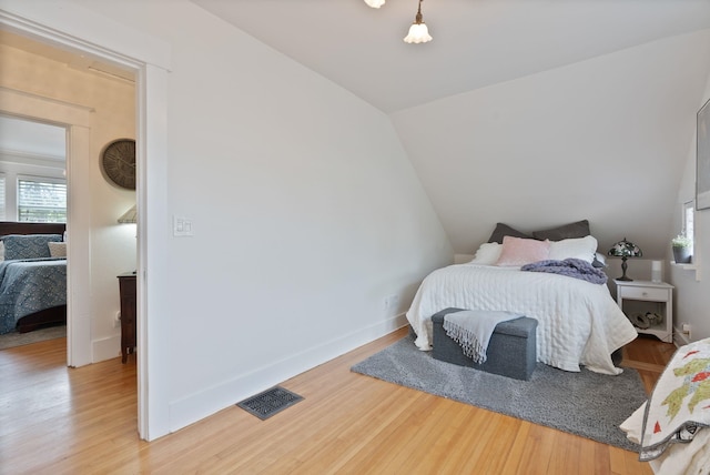 bedroom featuring wood finished floors, vaulted ceiling, and baseboards