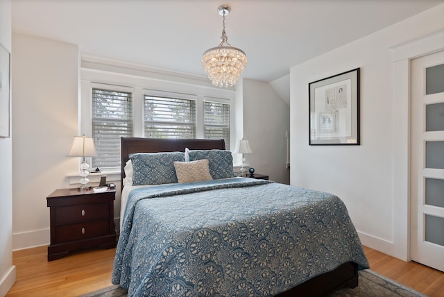 bedroom featuring wood finished floors, a chandelier, and baseboards
