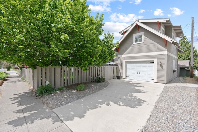 view of property exterior with fence, concrete driveway, and a garage