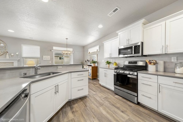 7919 W 55th Ave, Spokane, WA 99224 - kitchen featuring appliances with stainless steel finishes, a sink, white cabinets, light wood-type flooring, and a textured ceiling