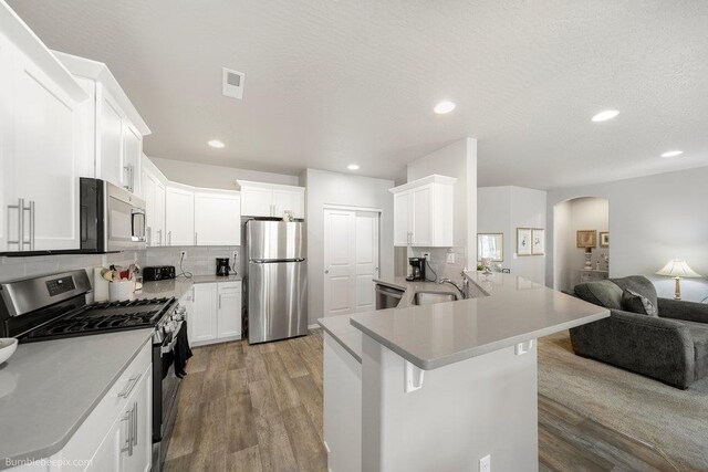 7919 W 55th Ave, Spokane, WA 99224 - kitchen with stainless steel appliances, open floor plan, arched walkways, wood finished floors, and recessed lighting