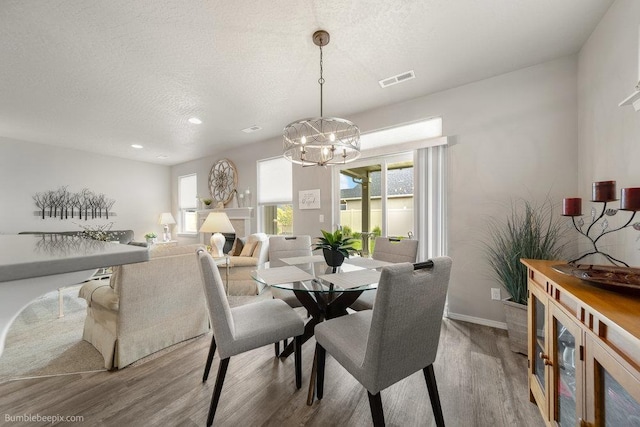 7919 W 55th Ave, Spokane, WA 99224 - dining area featuring wood finished floors, a chandelier, a textured ceiling, and baseboards