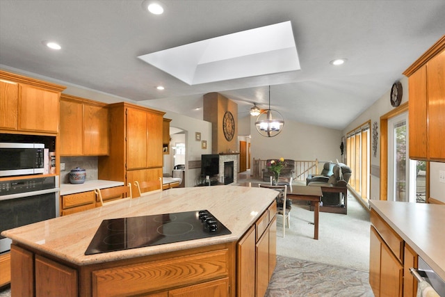 10610 N Iroquois Dr, Spokane, WA 99208 - kitchen featuring black electric cooktop, oven, a skylight, stainless steel microwave, and open floor plan