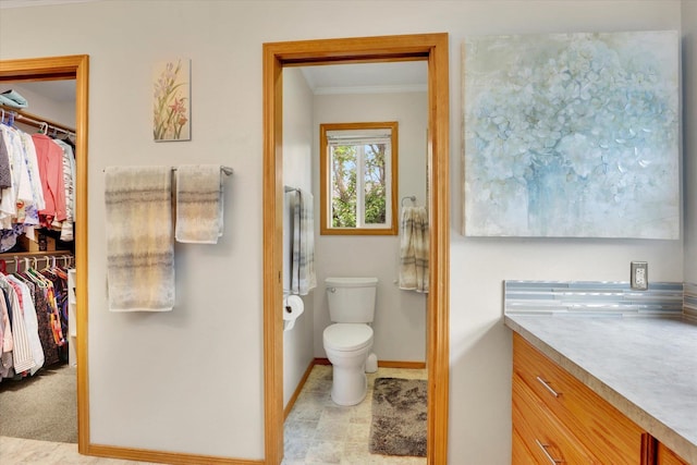 10610 N Iroquois Dr, Spokane, WA 99208 - bathroom featuring crown molding, toilet, baseboards, a walk in closet, and vanity
