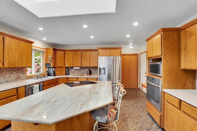10610 N Iroquois Dr, Spokane, WA 99208 - kitchen with appliances with stainless steel finishes, a sink, a kitchen breakfast bar, a center island, and decorative backsplash