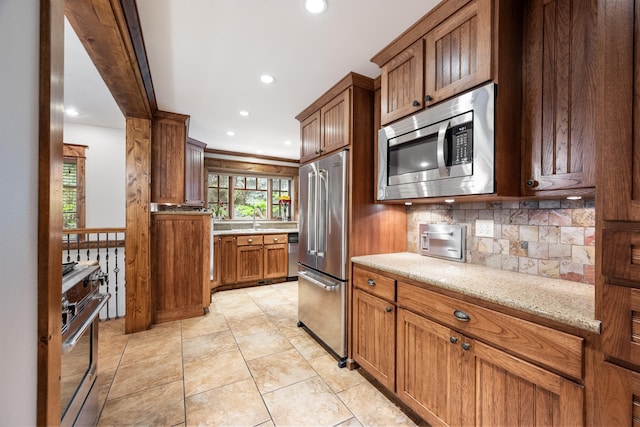 10204 N Wellen Ln, Spokane, WA 99218 - kitchen with high quality appliances, decorative backsplash, recessed lighting, brown cabinets, and light stone counters