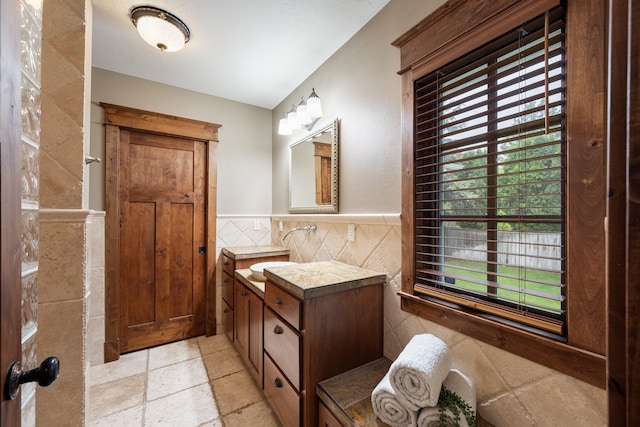10204 N Wellen Ln, Spokane, WA 99218 - bathroom featuring tile walls, stone tile flooring, vanity, and a wainscoted wall