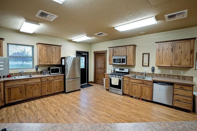 6701 N Idaho Rd, Newman Lake, WA 99025 - kitchen with stainless steel appliances, a sink, light wood-type flooring, and a textured ceiling