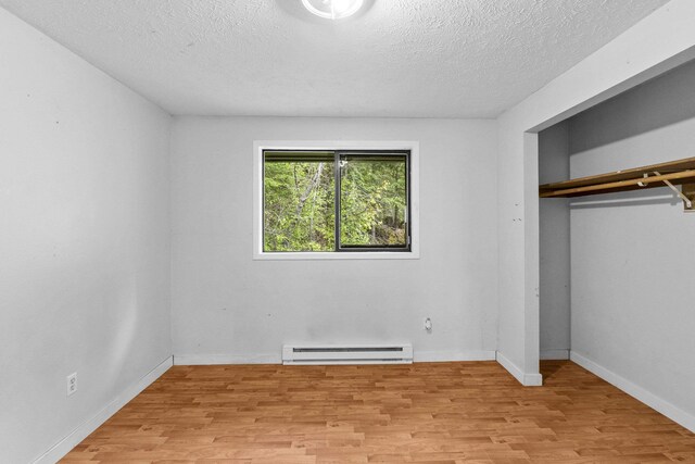 2362 Nicholson Rd, Elk, WA 99009 - unfurnished bedroom featuring a baseboard heating unit, light wood-style flooring, a textured ceiling, a closet, and baseboards