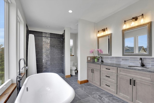 39980 Lake Summit Dr, Loon Lake, WA 99148 - full bath featuring toilet, a freestanding bath, double vanity, decorative backsplash, and tiled shower