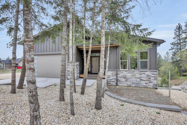 39980 Lake Summit Dr, Loon Lake, WA 99148 - mid-century inspired home featuring board and batten siding, concrete driveway, stone siding, and an attached garage