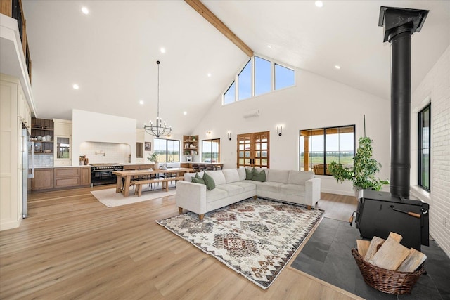 23114 W Mcfarlane Rd, Medical Lake, WA 99022 - living room featuring a wood stove, high vaulted ceiling, beamed ceiling, light wood-style flooring, and a chandelier