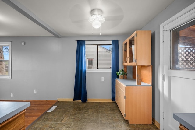 607 E Walton Ave, Spokane, WA 99207 - kitchen featuring a ceiling fan, stone finish floors, baseboards, glass insert cabinets, and light countertops