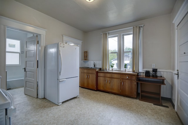 1608 E Pacific Ave, Spokane, WA 99202 - kitchen with freestanding refrigerator, brown cabinets, plenty of natural light, wainscoting, and light floors