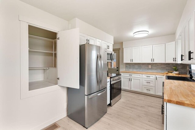 2417 E Nebraska Ave, Spokane, WA 99208 - kitchen featuring butcher block counters, appliances with stainless steel finishes, a sink, tasteful backsplash, and white cabinets