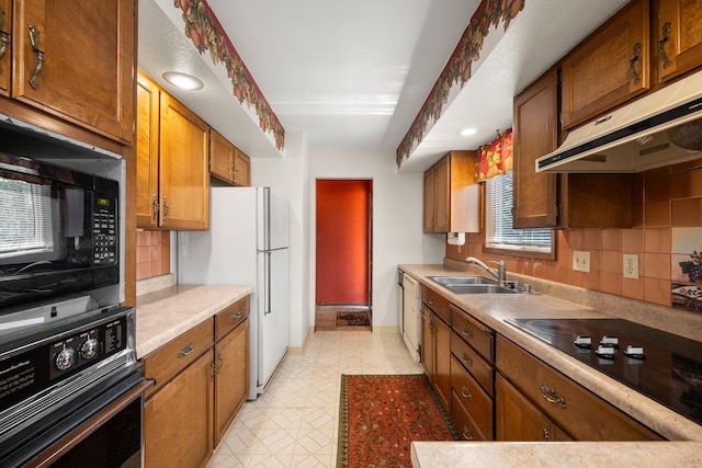 4796 W Gibson Dahl Rd, Clayton, WA 99110 - kitchen with black appliances, under cabinet range hood, a sink, brown cabinets, and tasteful backsplash