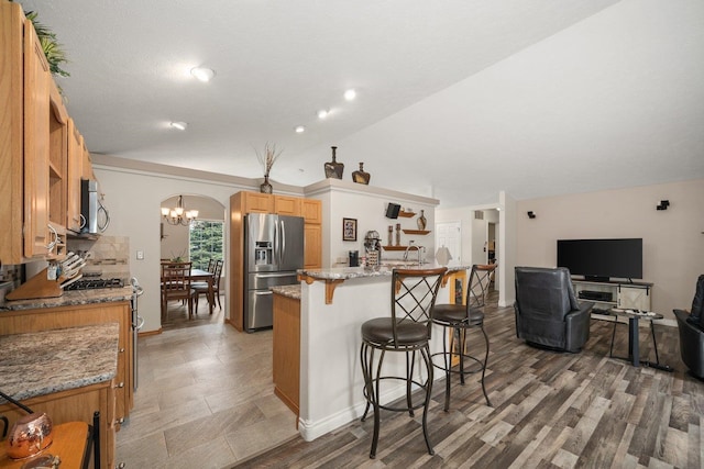 17110 W Boone Ln, Medical Lake, WA 99022 - kitchen with stainless steel appliances, a breakfast bar, light stone counters, lofted ceiling, and a chandelier